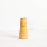 A small tapered ceramic vase in a warm sandy beige color with horizontal bands, standing on a white surface against a white background.