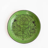 A round, green Huancito Mexican burnished ceramic hand-painted plate with floral designs.
