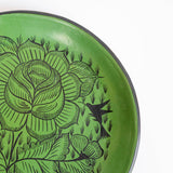 Close-up of a green Huancito ceramic plate with white hand-painted floral and bird motifs common in Michoacan.