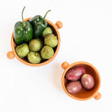 Two terracotta Mexican ceramic bowls with round ball side handles on a white background. Burnished ceramics from Nahuatl community in Michoacan, Mexico.