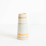 A small ceramic vase / bedside carafe with a textured off-white gray hue and two warm beige horizontal bands, shown on a seamless white background.