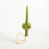 A green Oaxacan beeswax taper candle with sculpted flower details around the middle, handcrafted in Oaxaca using artisanal techniques