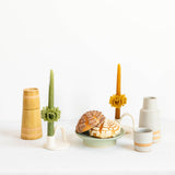 A table setting with two Oaxacan beeswax taper candles, Mexican sweet bread and Mexican ceramic carafes.