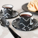 Two black and white expresso sets cups and saucers on a kitchen counter