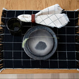 Black and white checkered placemat with a bowl and cups on a wooden table