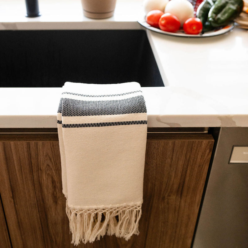 A side view of the natural cotton hand towel hanging on a kitchen sink