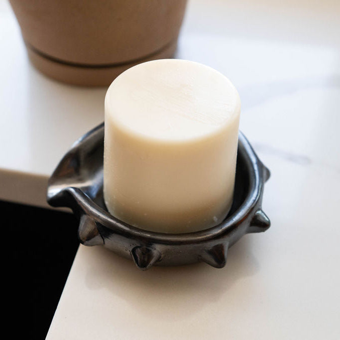 Black barro negro ceramic soap dish with spiked rim on a white countertop next to a kitchen sink