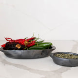 Two barro negro (black ceramic) bowls with spices on a marble surface