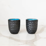 Two black Hammered Modern Mexican ceramic cups with a blue interior on a white background