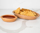 Terracotta Ceramic Clay Bowl of tortilla chips with a small container of salsa on a marble surface