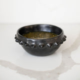 Mexican Barro Negro black ceramic bowl with pointed spikes on the rim on a white surface