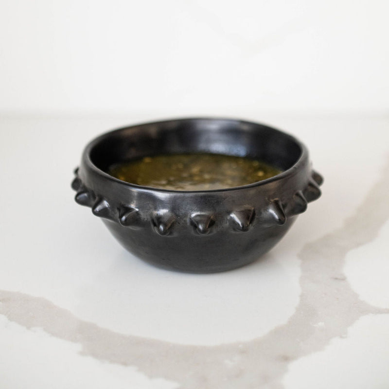 Mexican Barro Negro black ceramic bowl with pointed spikes on the rim on a white surface