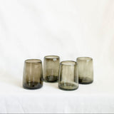 Four smoked glass tumblers on a white background