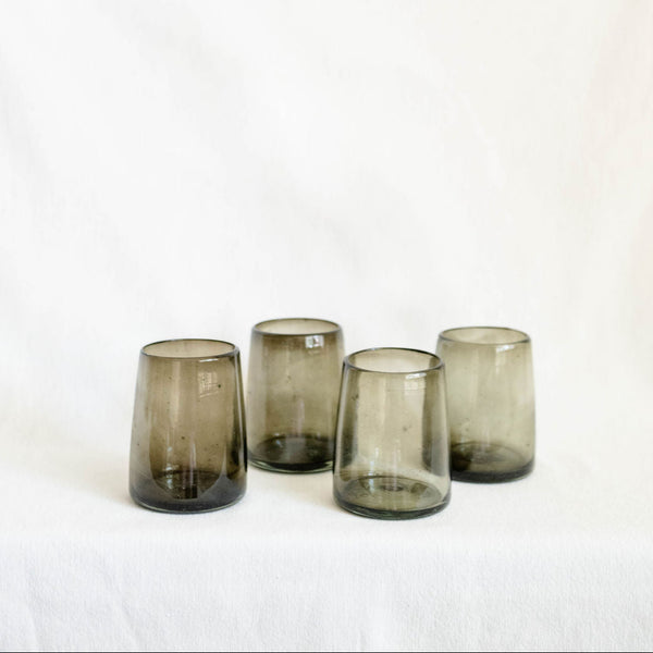 Four smoked glass tumblers on a white background