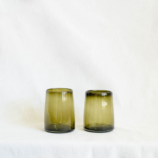 Two green glass tumblers on a white background