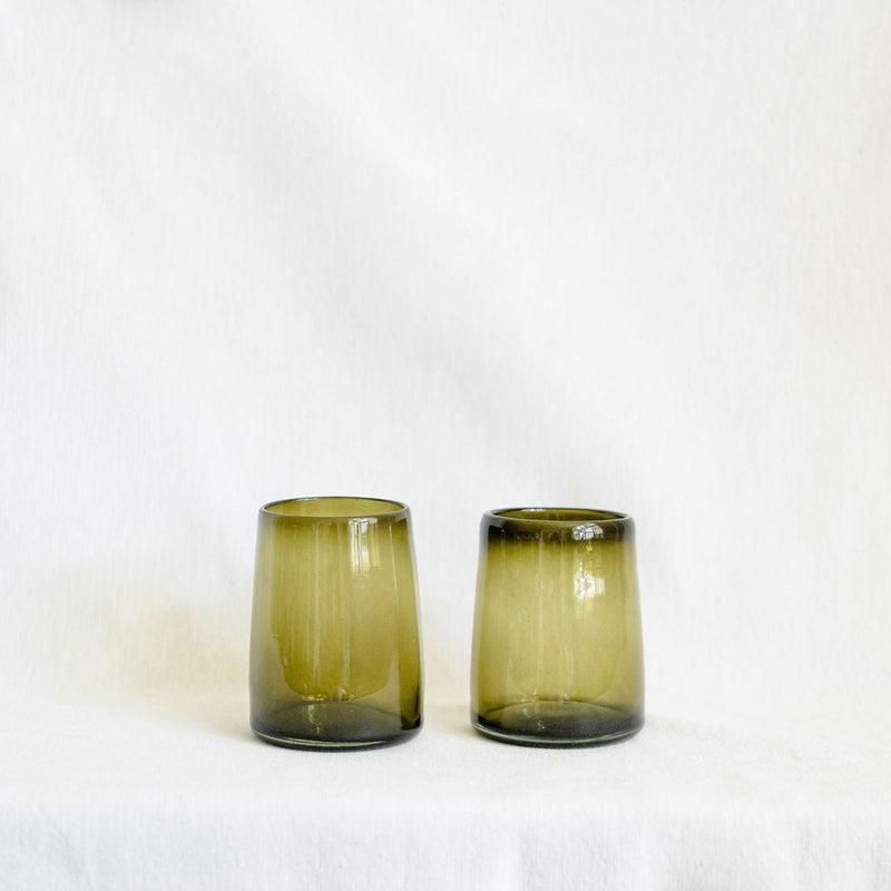 Two green glass tumblers on a white background