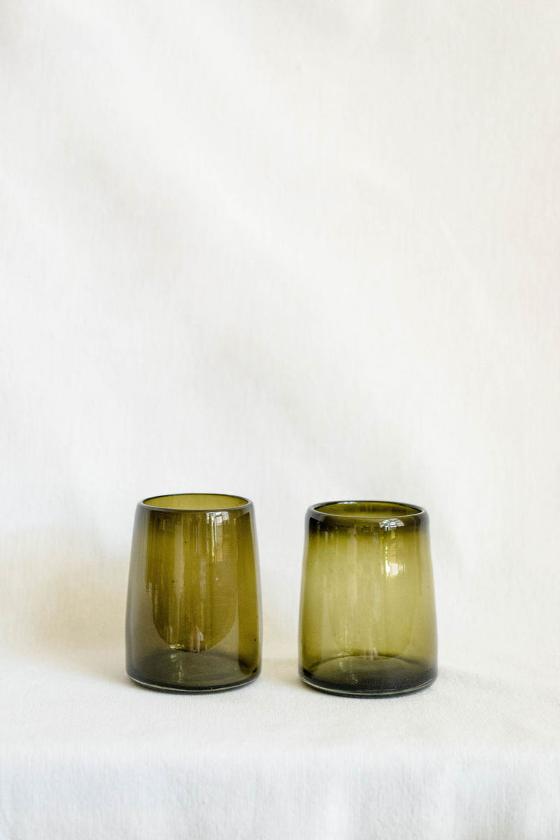 Two green glass tumblers on a white background