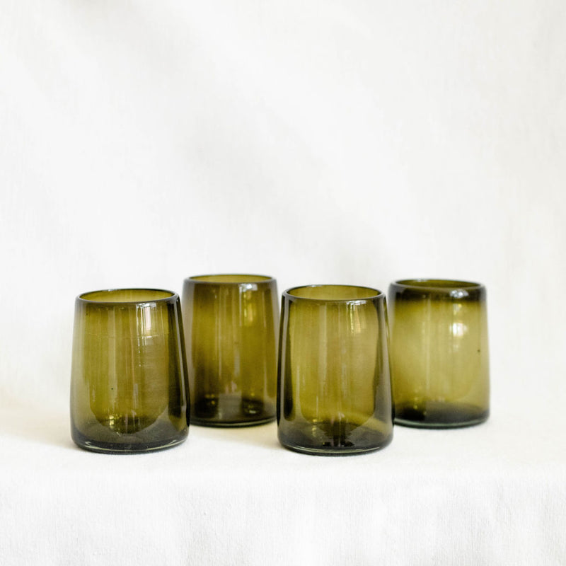 Four green glass tumblers on a white background