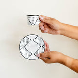 Hand holding an enamel espresso cup and saucer