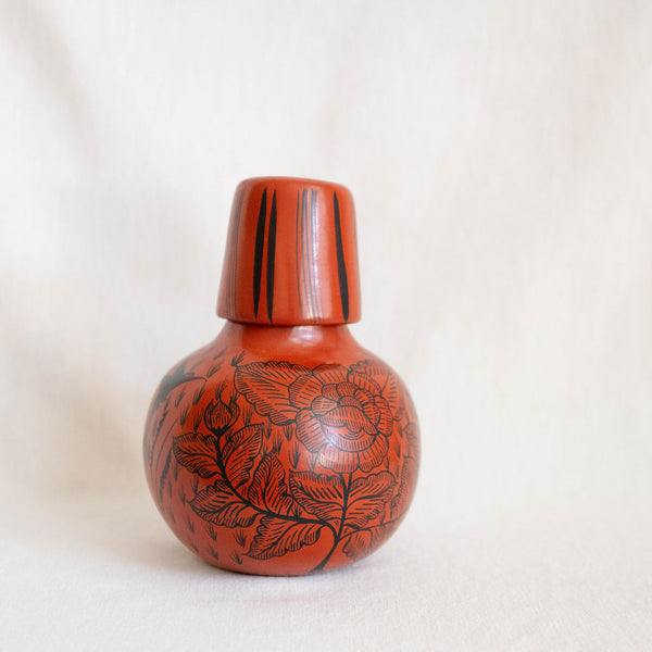 Decorative red vase with black floral patterns on a white background