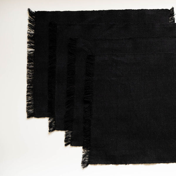 Set of black placemats with frayed edges on a white background