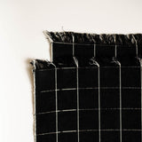 Black cotton woven napkins with white grid pattern on a white background