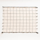 Grid-patterned napkin with tassels on a white background