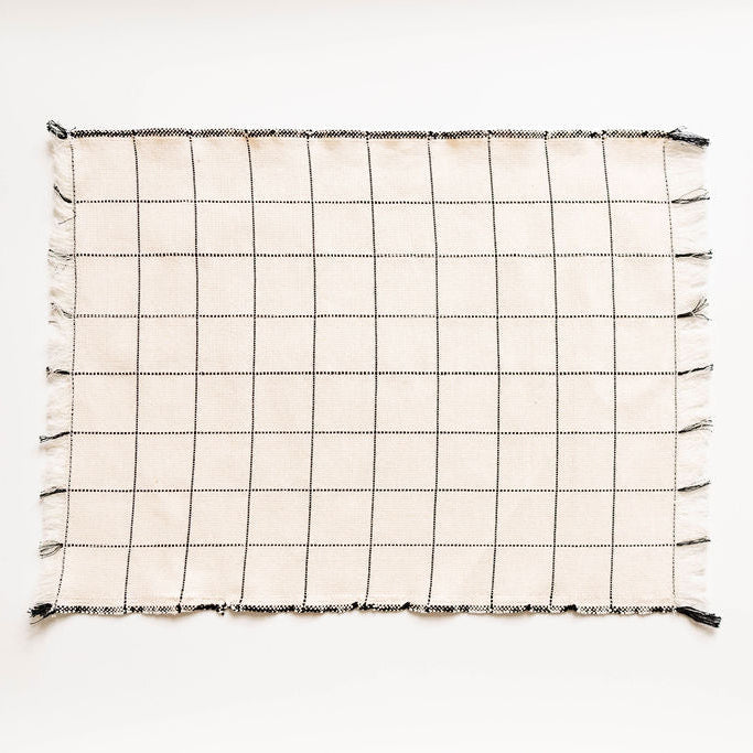 Grid-patterned napkin with tassels on a white background
