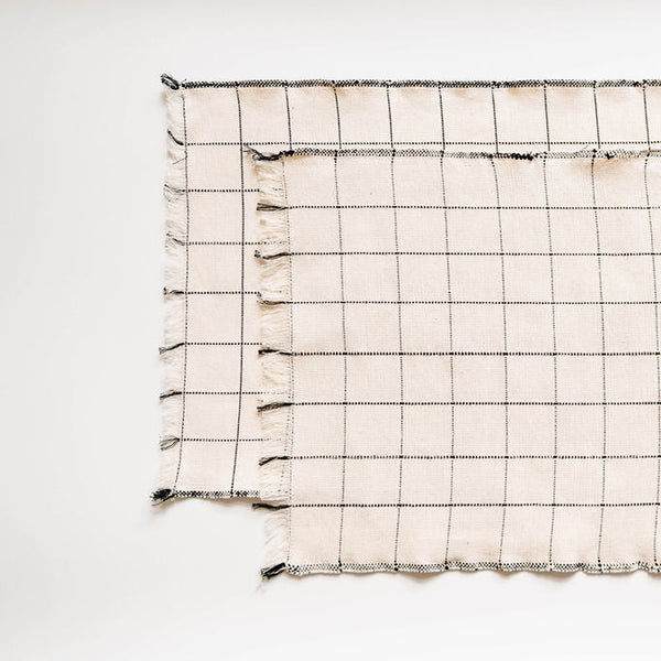 Grid-patterned napkins with tassels on a white background
