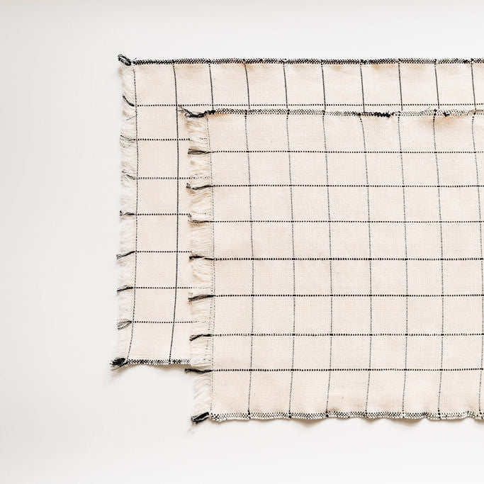 Grid-patterned napkins with tassels on a white background