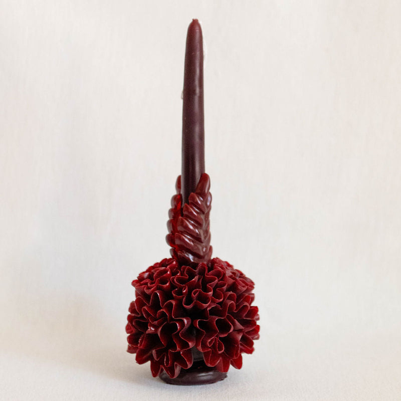 Burgundy Oaxaca Taper Beeswax Candle with floral base on a light beige background