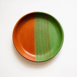 Ceramic plate with orange and green design on a white background