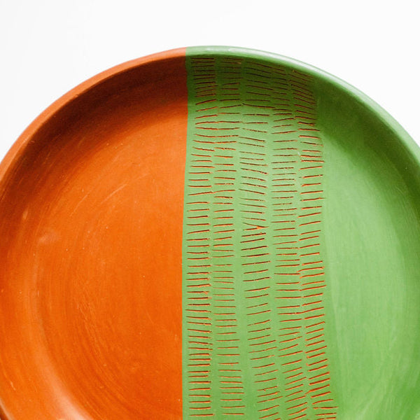 Ceramic plate with orange and green color scheme on a white background