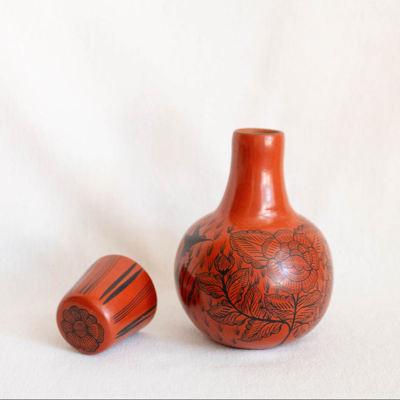 Red ceramic vase with black patterns on a white background