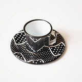 enamel expresso cup and saucer with black and white geometric pattern on a white background