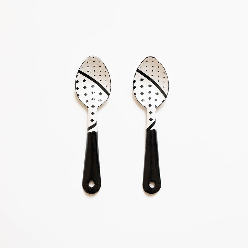 Two black-handled spoons with decorative patterns on a white background