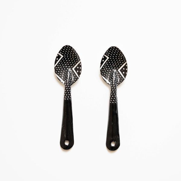 Two black spoons with decorative patterns on a white background