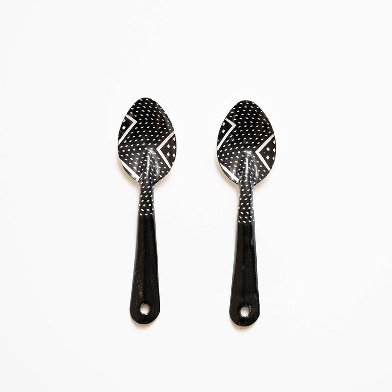 Two black spoons with decorative patterns on a white background