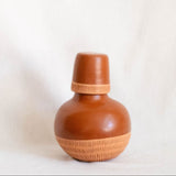Ceramic bottle with woven design on a white background