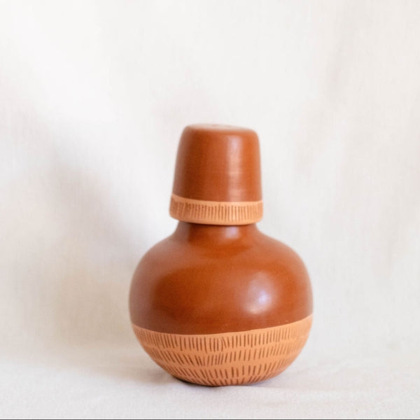 Ceramic bottle with woven design on a white background