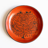 Red burnished ceramic plate from Huancito, Michoacan with black floral designs on white background