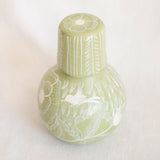Light green ceramic bottle with decorative patterns on a white background