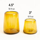 Two amber glass handblown tumblers with measurements on a white background