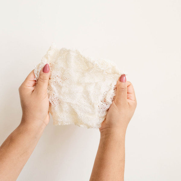 Hands holding an agave ayate washcloth  against a plain background