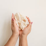 Hands holding an agave ayate washcloth against a plain background