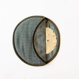 A hunter green cloth woven tortilla warmer or taco holder with a dark fabric body, dark trim, and a curved opening showing a tortilla inside, photographed on a plain white background.