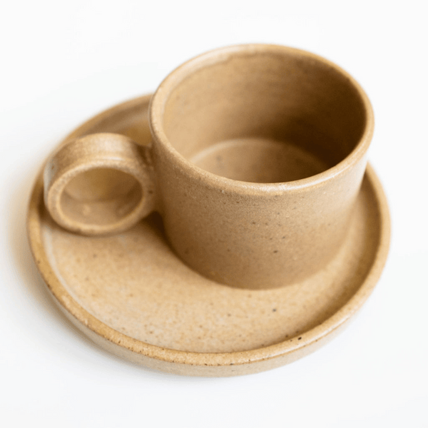 Ceramic Cup and Saucer Set in beige / tan color with sleek finish on white surface
