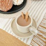 Vanilla Creme Mexican Ceramic Cup and Saucer Set featuring a wide ear handle and cream-colored finish with subtle speckles. Top view showing it filled with coffee and Mexican cinnamon sticks.