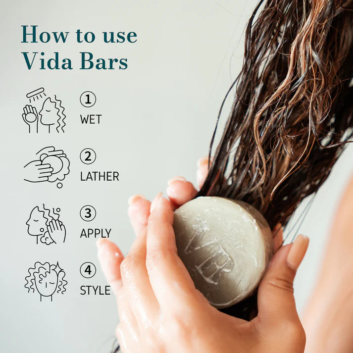 Person holding a Vida Bars Leave-In Conditioner bar against their hair, showcasing the eco-friendly and compact design of the product. The bar has a blue hint with a smooth texture, symbolizing its natural ingredients and sustainable beauty approach.