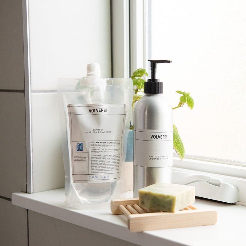 Sustainable bathroom essentials: refillable body wash pouch, body wash in aluminum pump bottle, soap bar and wood soap dish